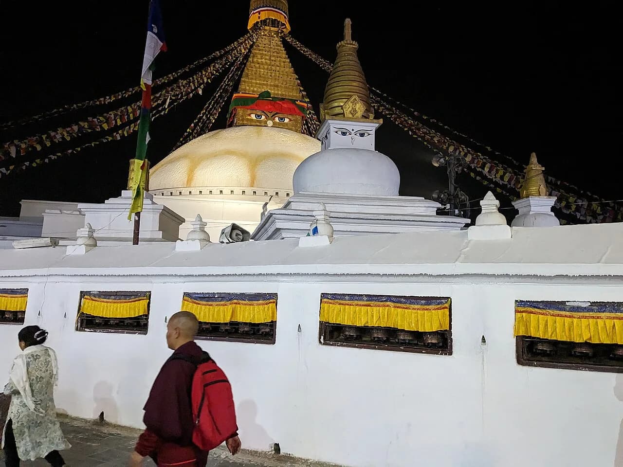 Prayer wheels beneath the illuminated Boudhanath Stupa